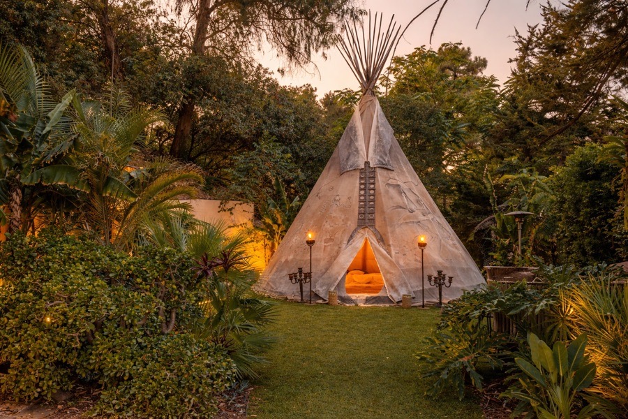 The teepee at twilight, lit by torches